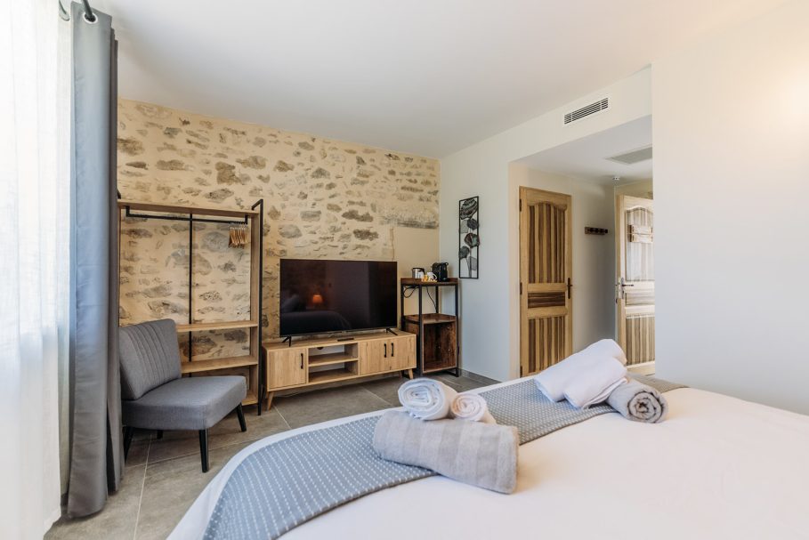 Chambre avec mur en pierre apparente et mobilier bois naturel – lieu privé de retraite Access Flow