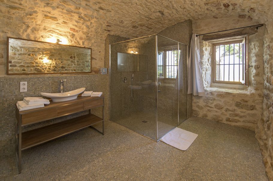 Salle de bain voûtée en pierre avec douche mosaïque et vasque sur meuble bois – retreat luxe absolu