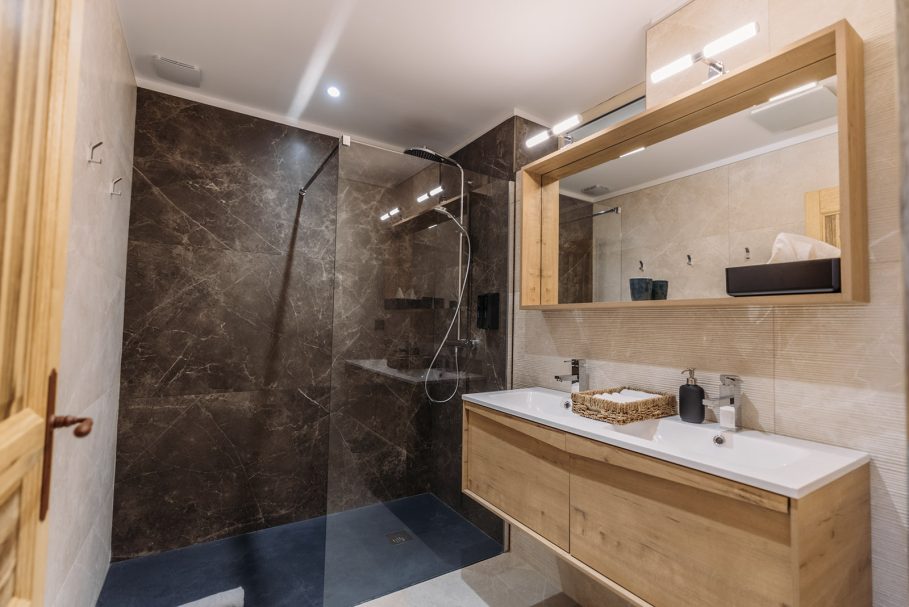 Salle de bain avec douche à l'italienne en marbre foncé et meuble en bois clair – retreat haut de gamme