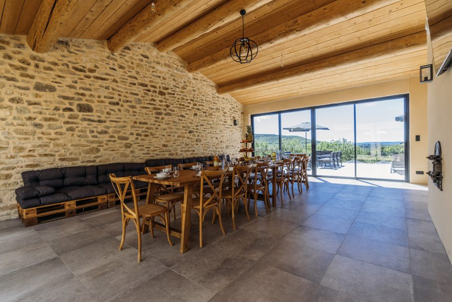 Salle de repas en pierre apparente et poutres bois, ouverte sur la nature – retreat de luxe Access Flow